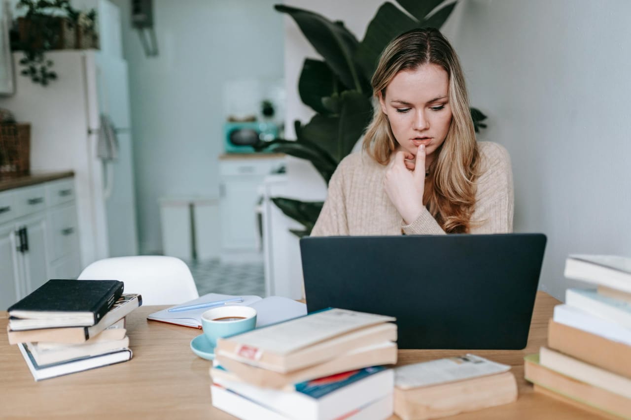 A young graduate sitting at a desk writing their first CV on a laptop